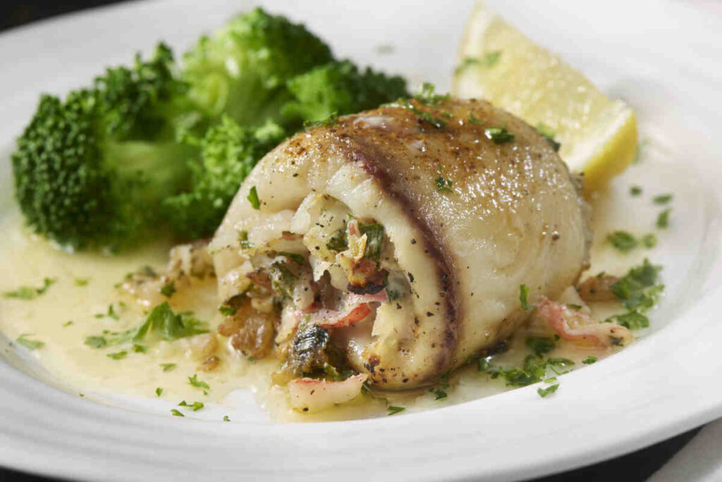 Involtini di pesce dorati ripieni su piatto con cremina e broccoletti