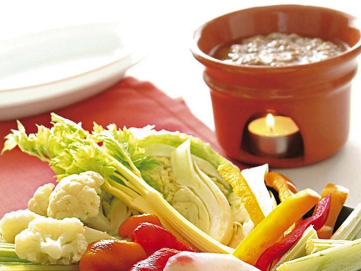 <p>Lava sotto l’acqua fredda 10 <b>acciughe sotto sale</b> e leva lisca e coda. Sbuccia 10 <b>spicchi di aglio,</b> togli il germoglio e affettali fini. Metti le acciughe e l’aglio in un tegame, meglio se di coccio, unisci 2,5 dl di <b>olio extravergine</b> e fai cuocere per 30 minuti a fuoco basso (non devono assolutamente soffriggere), girando di tanto in tanto. Aggiungi 50 g di <b>burro</b> morbido a pezzetti e mescola.</p><p>Intanto prepara un pinzimonio di <b>verdure crude</b> (carote e peperoni, sedano, finocchi, ravanelli, cipollotto) <b>e cotte </b>(topinambur, cavolfiori, cavolo, cardi). Porta in tavola la bagna cauda su un fornelletto acceso per tenerla in caldo e accompagnala con le verdure.</p>