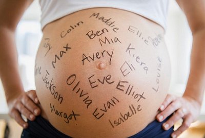 Mid section of pregnant woman with names written on her belly