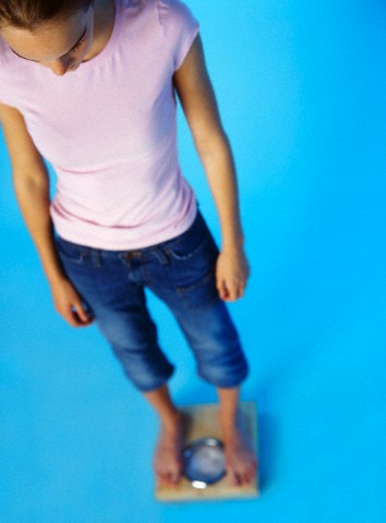 Teenage girl weighing herself