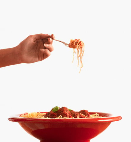 Hispanic woman holding fork of spaghetti