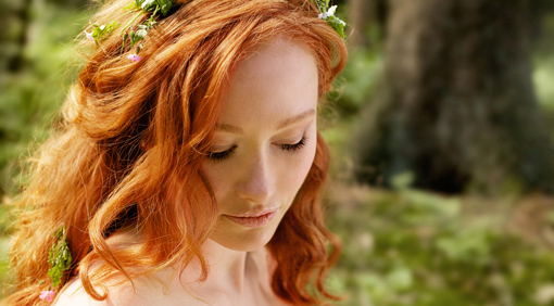 Beautiful woman with long red hair in forest