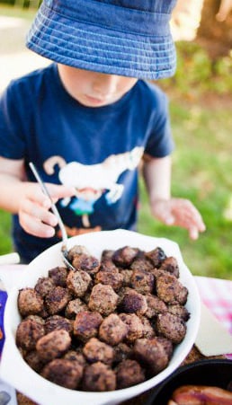 Little boy (4-5) picking meatballs from table