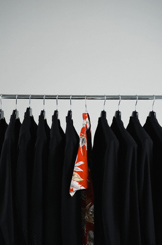 Hawaiian shirt hanging between black blazers