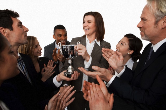 Businesswoman receiving trophy, colleagues clapping