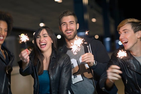 Friends celebrating New Year's Eve with sparklers outdoors