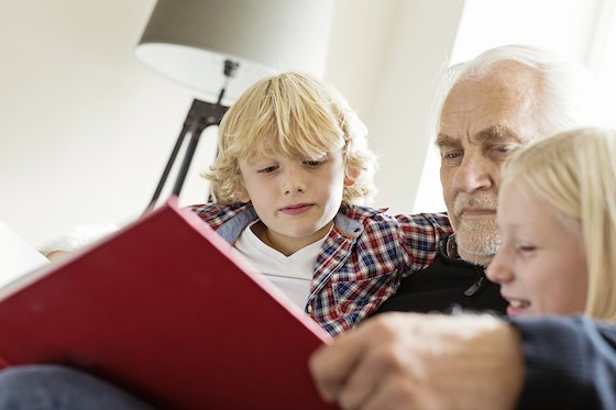 Grandfather reading book to grandchildren