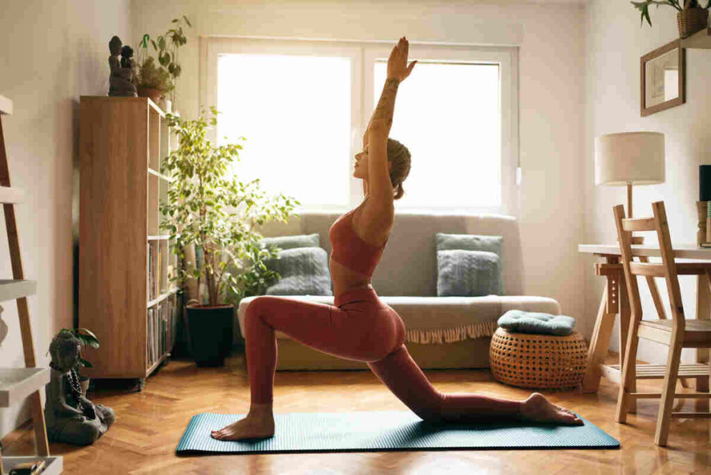 donna che fa stretching in casa con braccia e gamba piegata in avanti con sfondo di luce di finestra