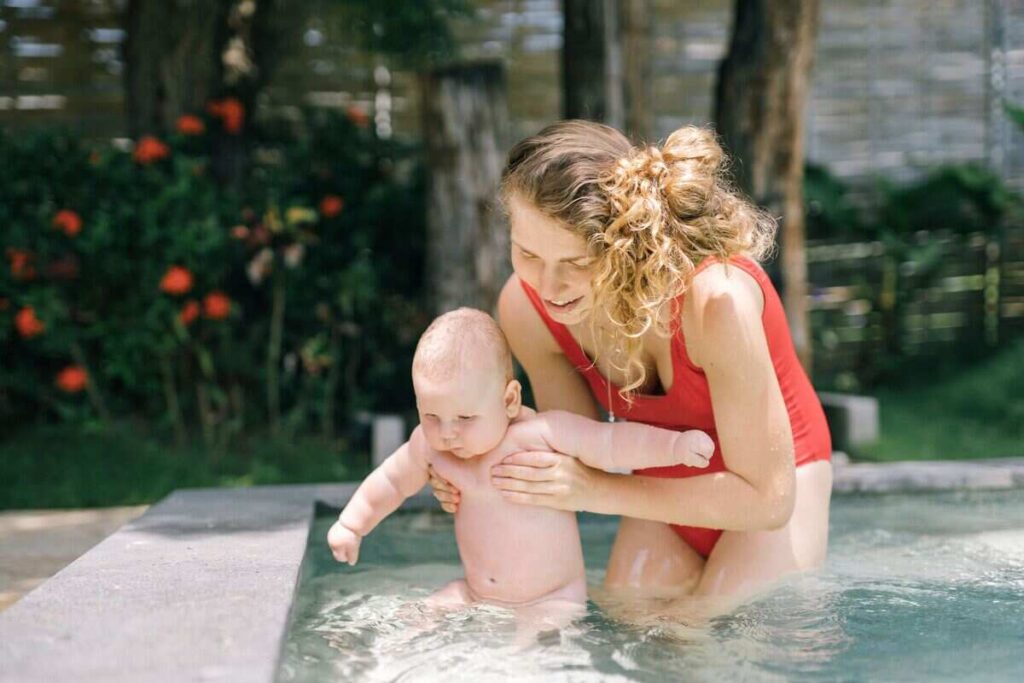 Mamma che aiuta bambino a stare in acqua in piscina