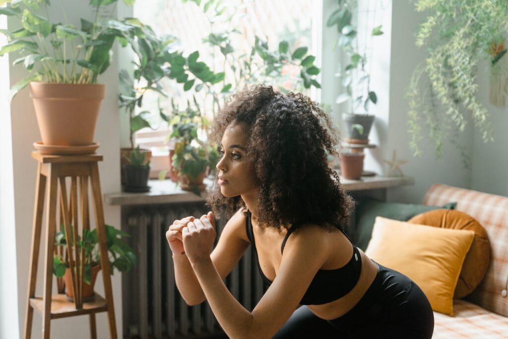 ragazza che si sta allenando a casa e fa squat
