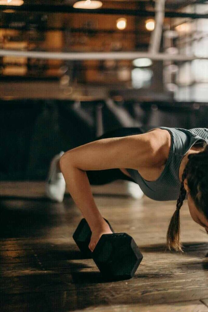 Donna che allena le braccia con pesi in plank