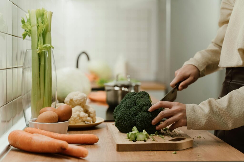 Donna che taglia broccoli su tagliere