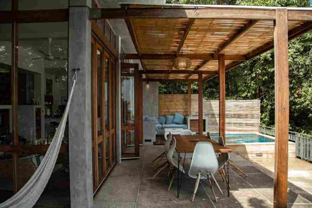 terrazzo casa con tavolini sedie e piscina sullo sfondo