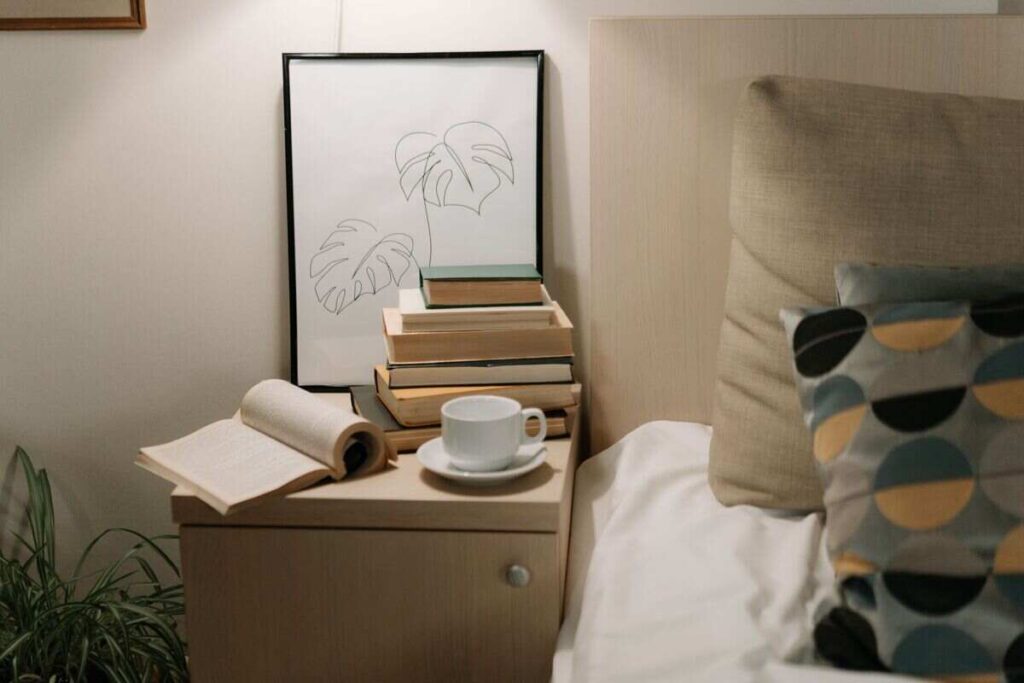comodino vicino letto con tazza, libro, quadro