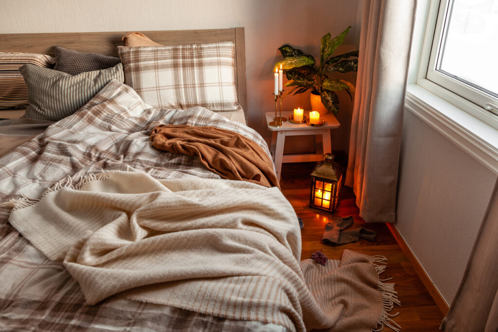 letto disfatto con candele e lanterne accese