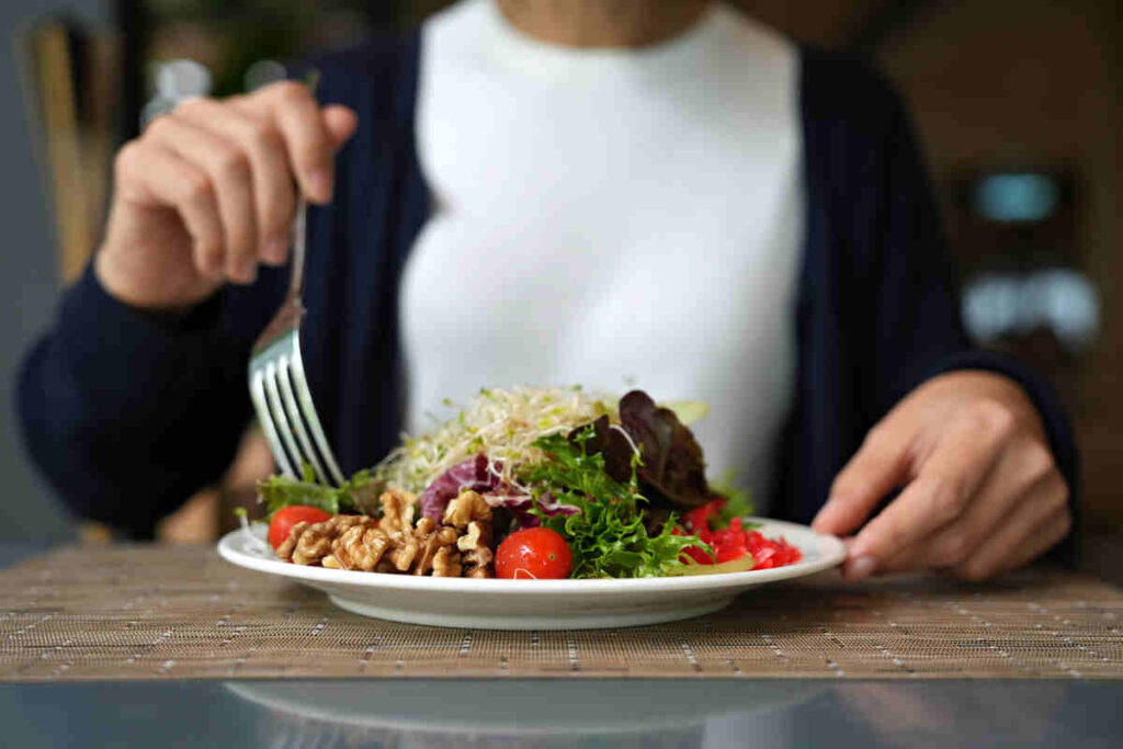 Immagine ritagliata di donna che ha insalata verde con germogli di erba medica, pomodorini, noci, verdure a foglia e olive