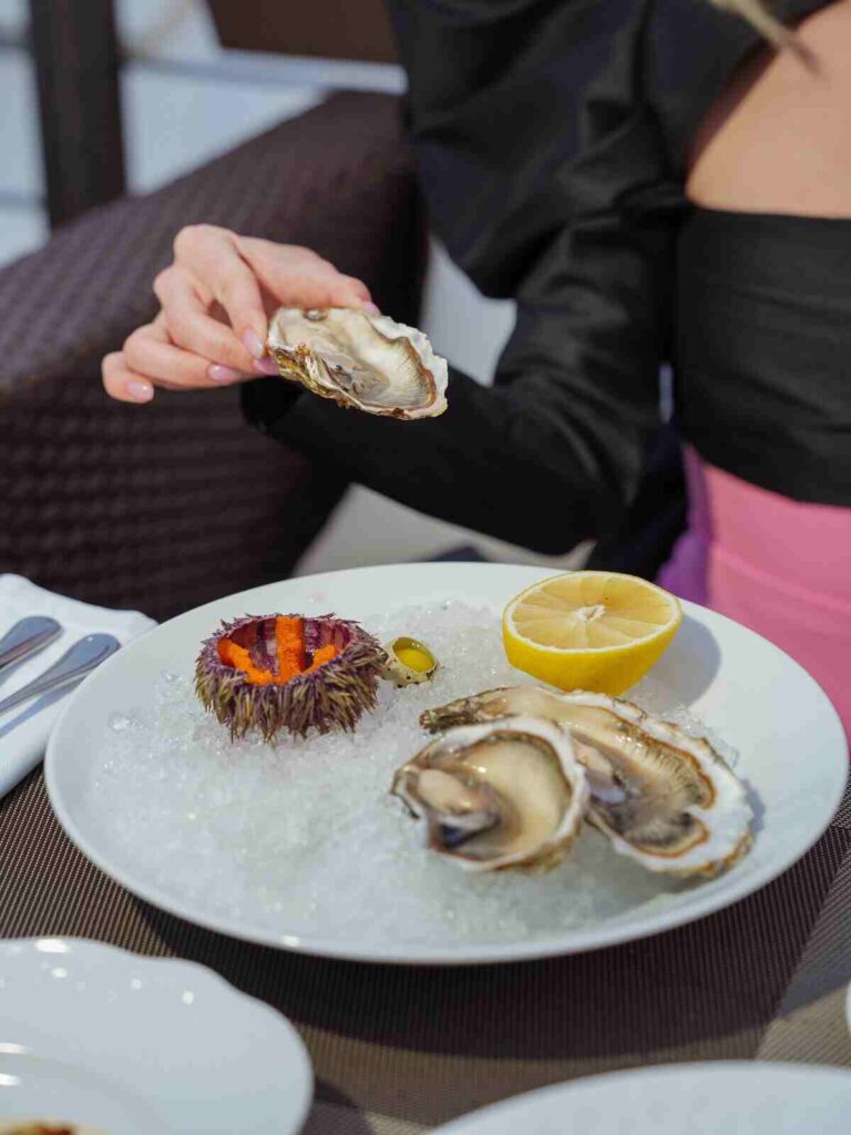 Donna seduta al tavolo che mangia molluschi