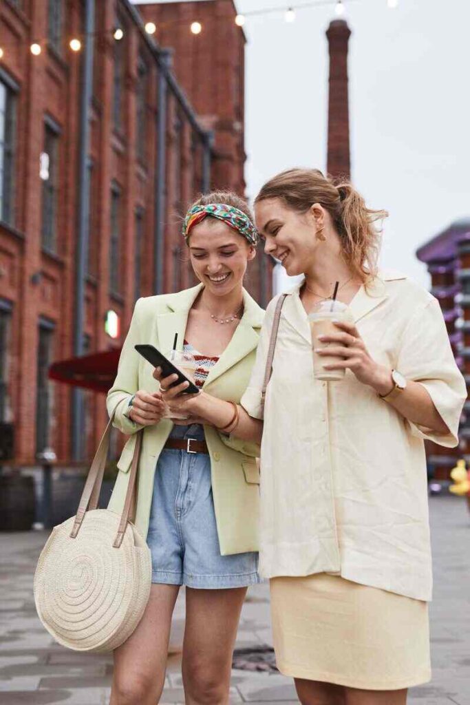 Due giovani donne in città che ridono e guardano il telefono