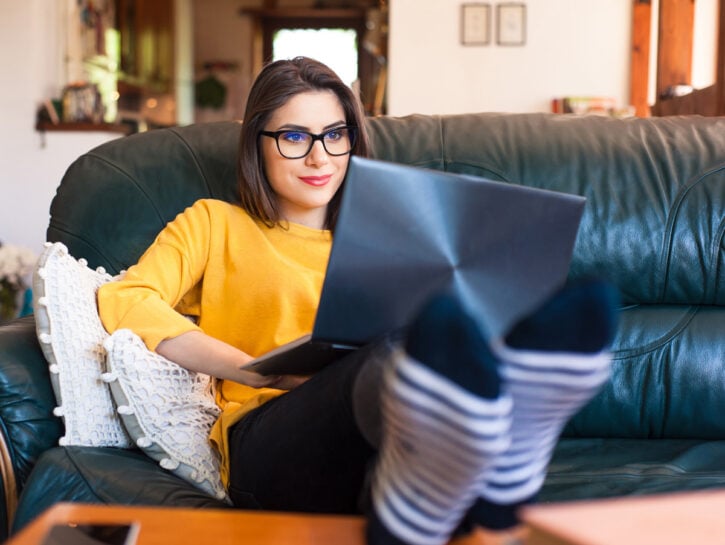 Ragazza scrive al computer sul divano