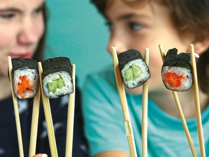 Bambini mangiano sushi bacchette