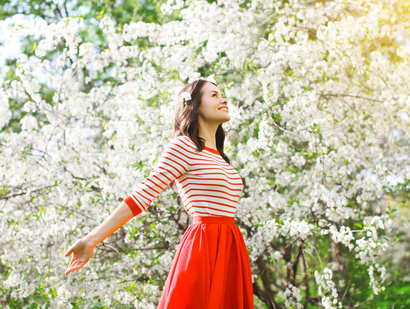 Ragazza rosso in mezzo alberi in fiore