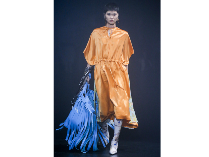 Un vestito arancio abbinato a una borsa con le frange blu di Balenciaga