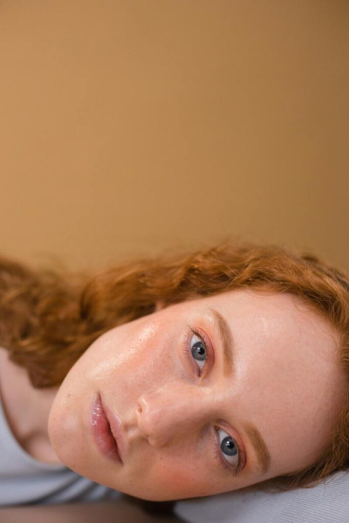 Donna con viso steso di lato, con capelli rossi e viso limpido e pulito 