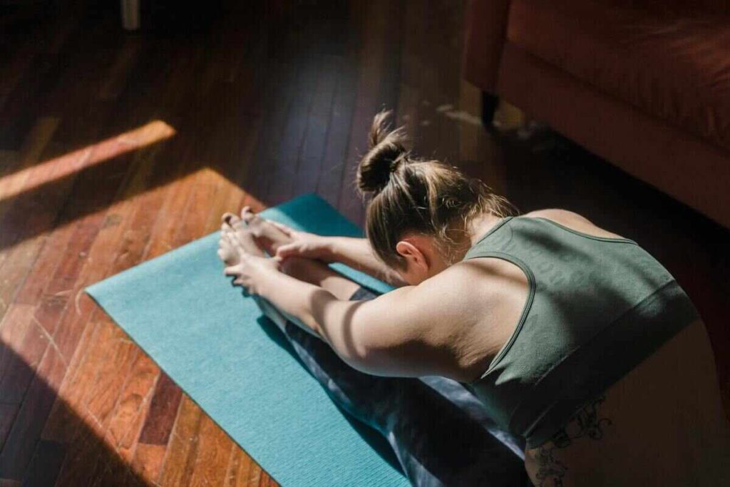 Donna che si piega sulle gambe sul tappetino in posizione yoga