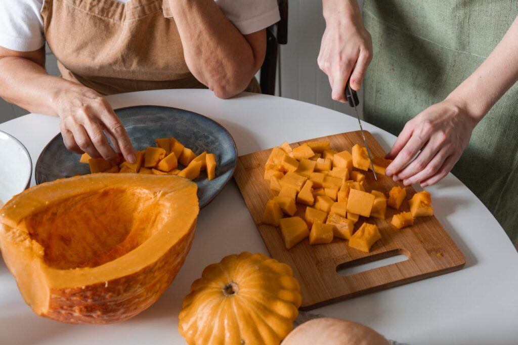 due ragazze tagliano a pezzetti la zucca sul tagliere