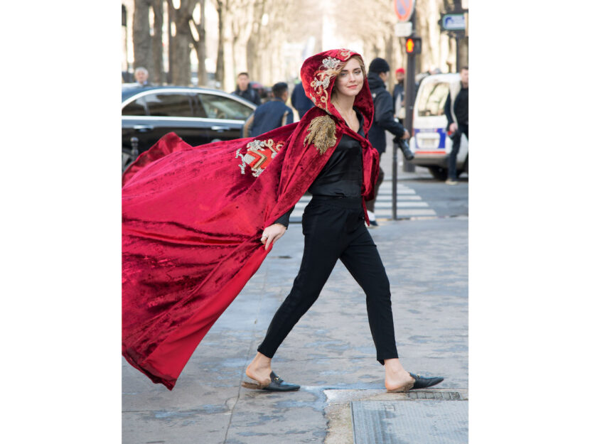Chiara Ferragni durante la fashion week di Parigi avvolta in un mantello rosso con cappuccio