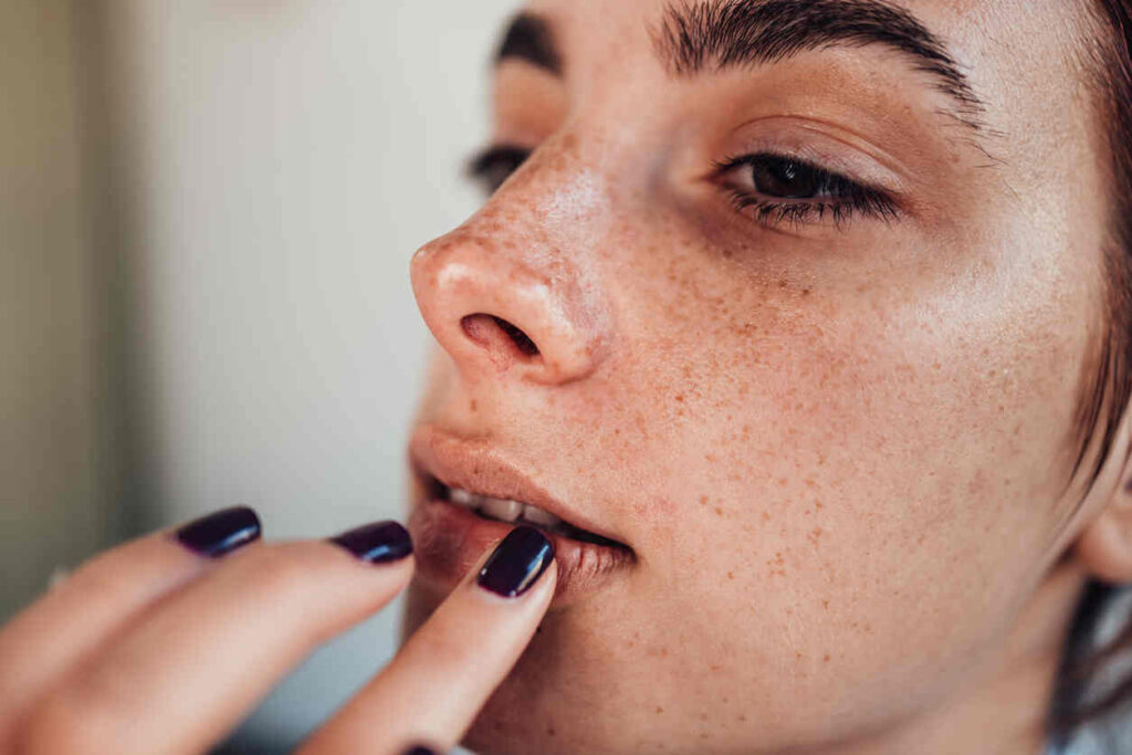 close-up donna con mani sul viso e unghia colore scuro