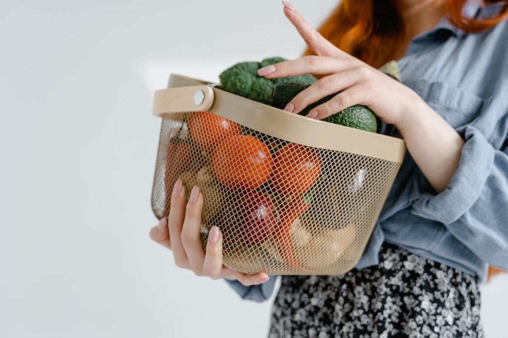 ragazza con in mano un cestello con frutta e verdura
