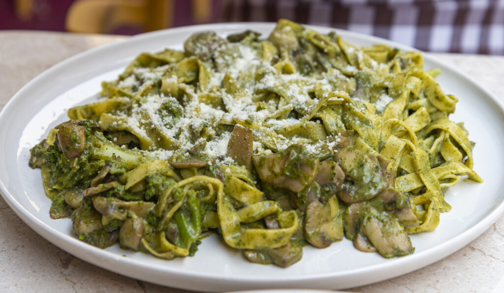 Tagliatelle verdi con grana e funghi porcini su piatto
