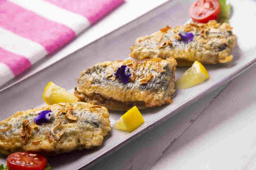 Tris di acciughe fritte decorate con fiorellini sopra su piatto
