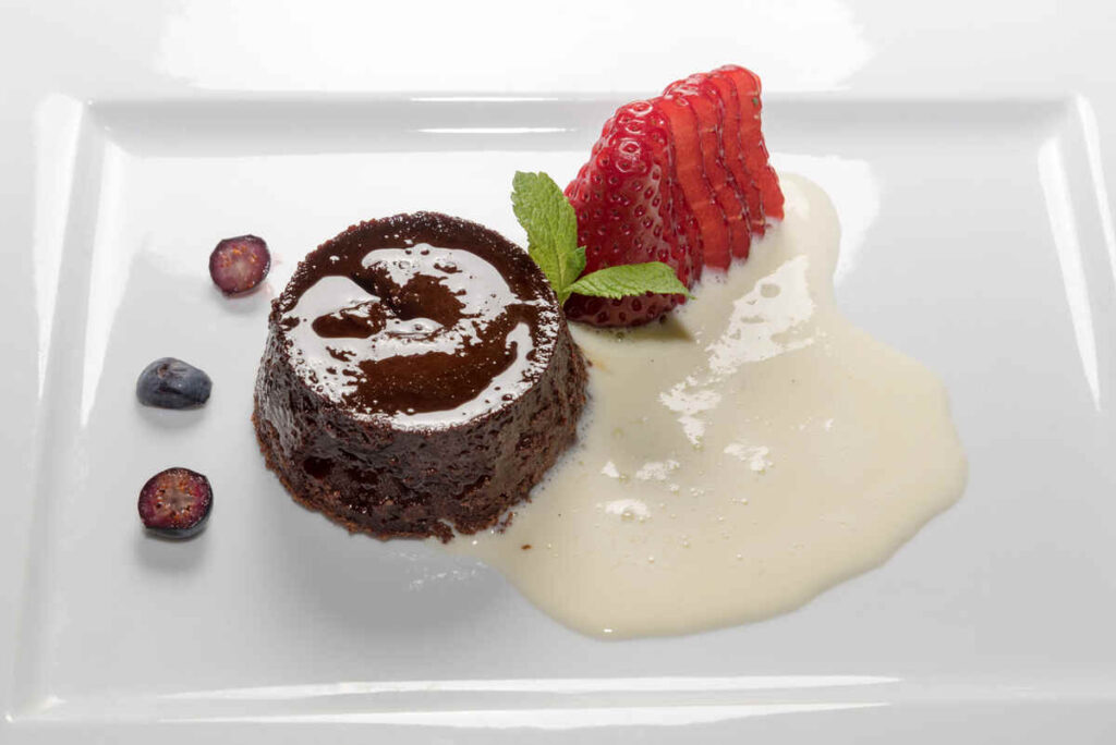 budino al cioccolato con gelato alla vaniglia e fragole in piatto