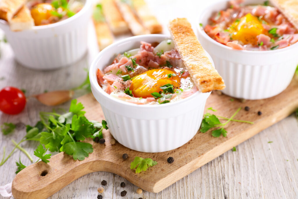 Uovo al forno in terrina con pancetta su tagliere