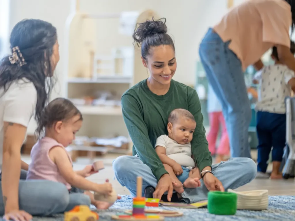 Due mamme con rispettivi bambini che giocano insieme in uno spazio sicuro