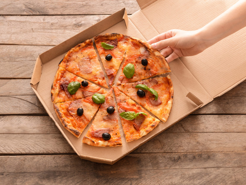 Pizza nel cartone con mano di donna