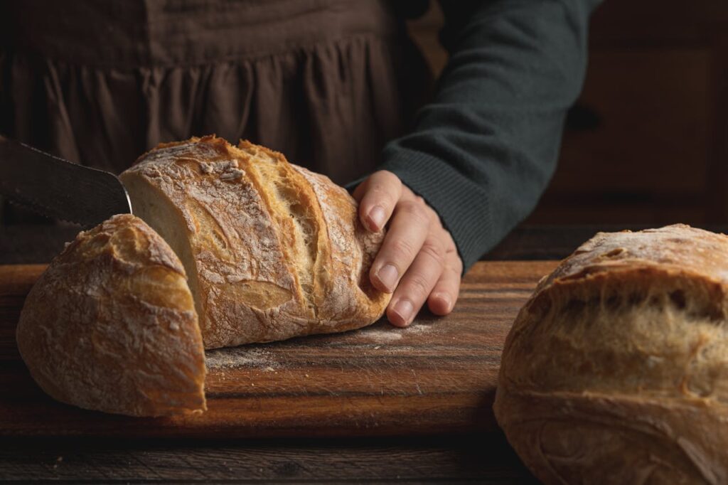 mani di donna che sta affettando il pane sul tagliere