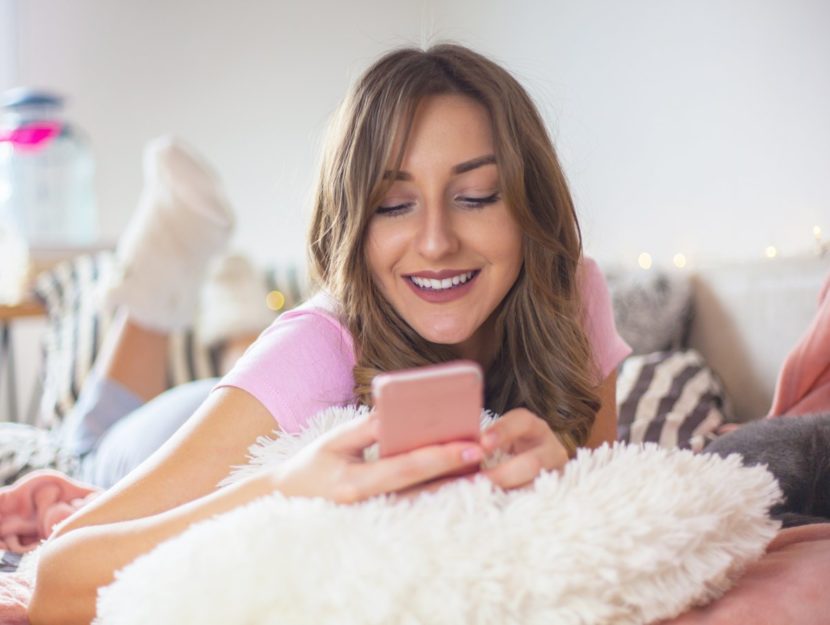Ragazza sul letto che usa il suo smartphon