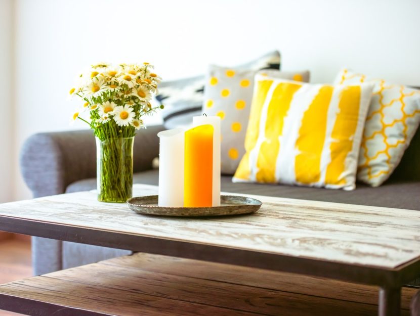 tavolino di legno con candele e vaso di margherite