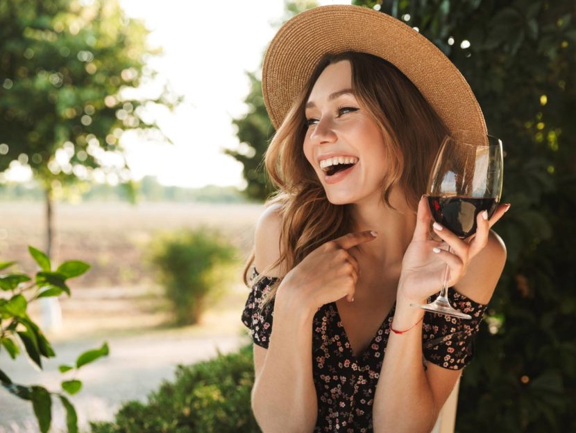 Ragazza sorridente beve vino all'aperto