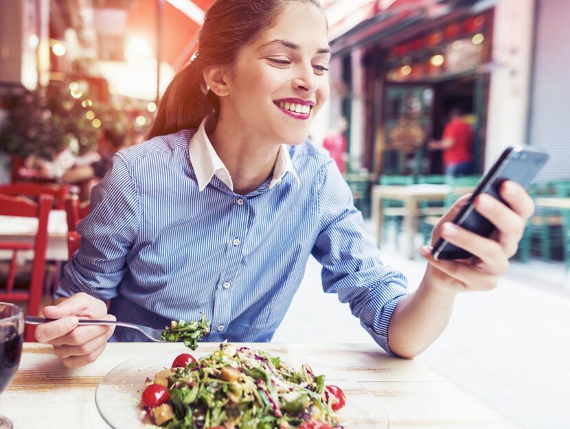 Ragazza che mangia e usa lo smartphone