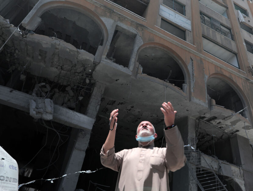 Un uomo palestinese di fronte alla Al-Jawhara Tower di Gaza City, colpita dagli attacchi aerei israe