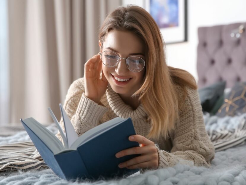 Donna legge un libro sul letto e sorride