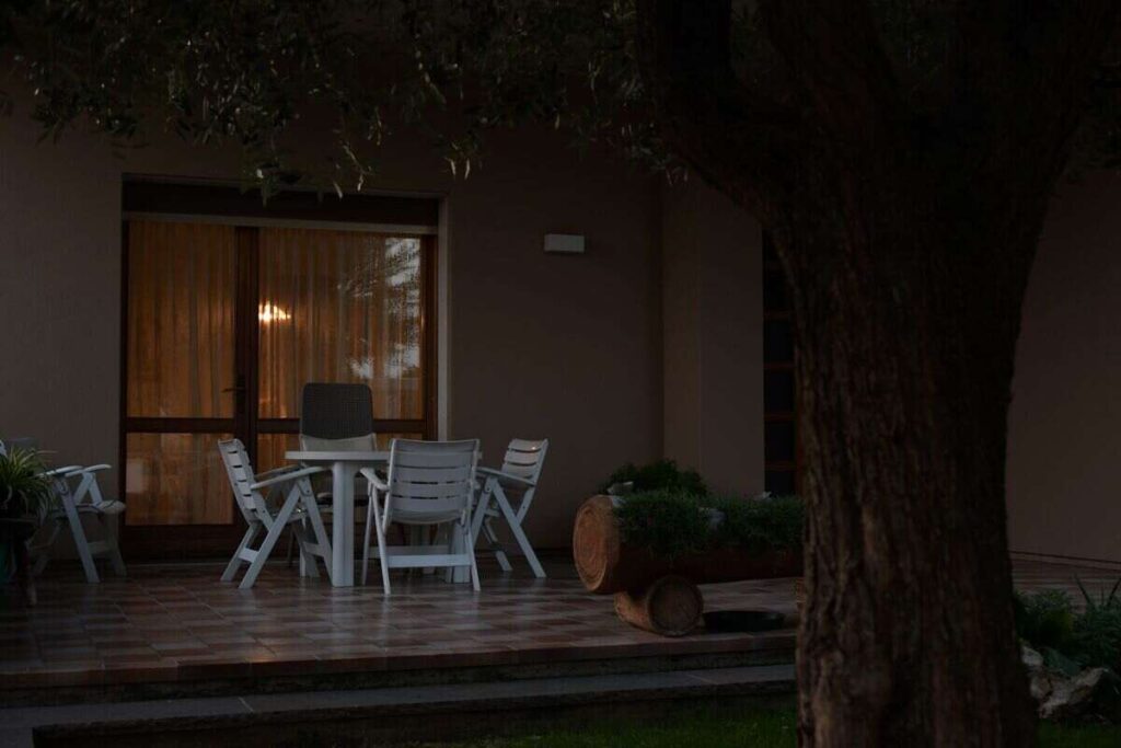 Cortile casa al buio con tavolino bianco e sedie