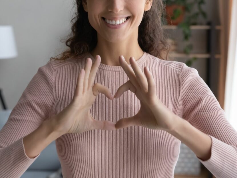 donn che fa il segno del cuore con le mani, sorriso, parole gentili