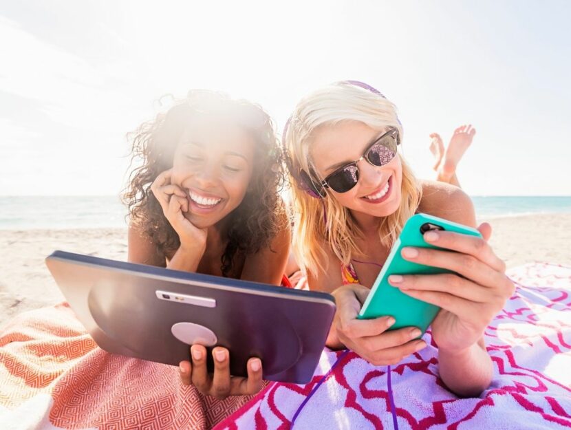 ragazze in spiaggia con smartphone e tablet, app per la spiaggia