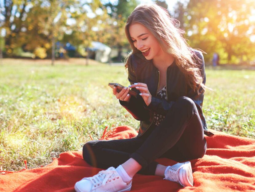 Ragazza sorride guardando smartphone