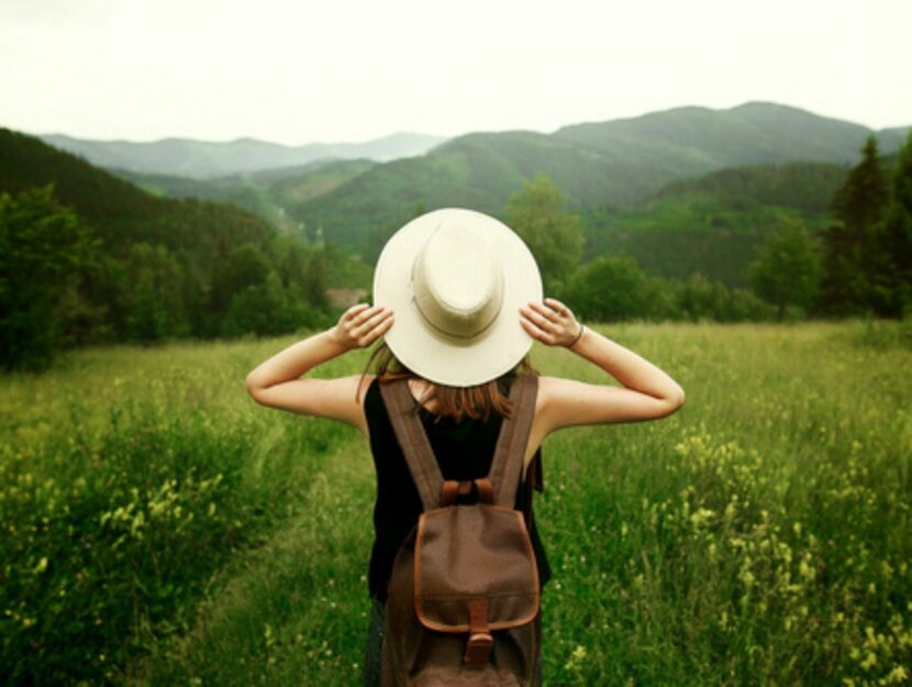 Ragazza con cappello e zaino che osserva la natura